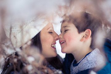 Beautiful mom tenderly holding her adorable, little boy and eskimo kisses him.