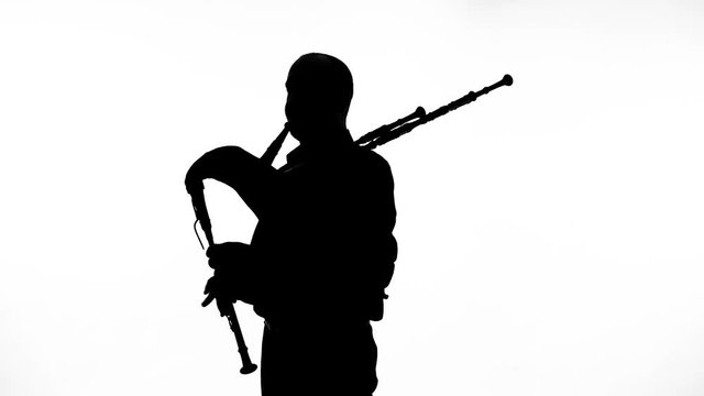 black silhouette on white background man playing bagpipes, national ethnic instrument close up