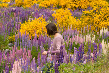 Relaxed young, casual, hispanic woman with short hair, walking in the woods, exploring a forest near the mountains in Patagonia, Argentina, full with colorful wild flowers, with copy space