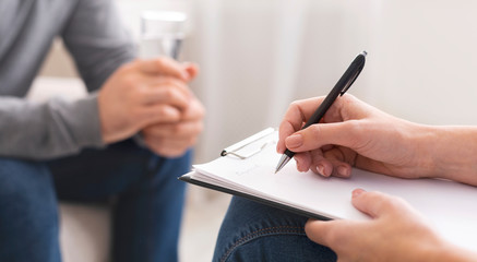 Psychologist taking notes during session with patient - obrazy, fototapety, plakaty