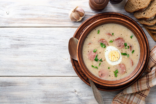 Traditional polish soup Zurek in ceramic bowl on wooden table. Top view. Copy space.