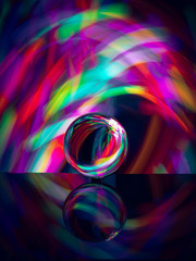crystal ball on reflective surface with colorful lights background