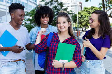 Jubelnde blone Studentin mit Freunden in der Stadt