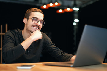 Young man working with computer, phone and tablet at the table while drinking coffee