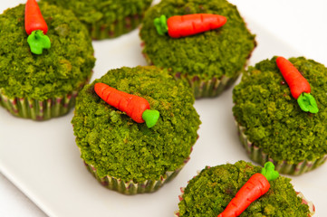 Green spinach cupcakes with candy carrots topping.