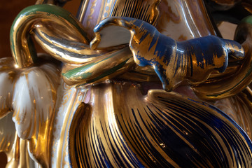 Very close view of antique ceramic vase, abundant gold glaze, selective focus, horizontal aspect