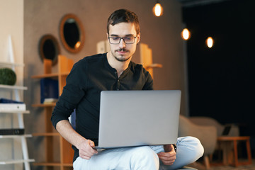 Young man sitting with computer. Freelancer in glasses working with laptop, project manager.