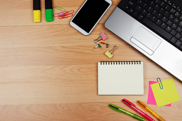 Smartphone and office supplies on wooden table, top view