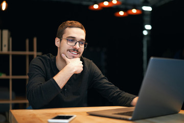 Young man working with computer, phone and tablet at the table while drinking coffee