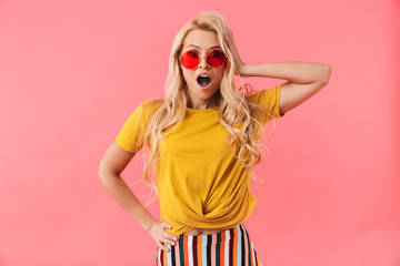 Shocked blonde woman in sunglasses with arm on hip
