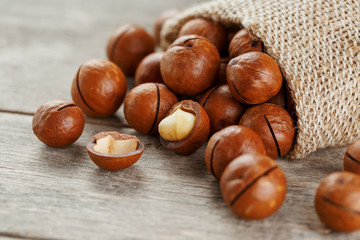 Macadamia nut on a wooden table in a bag, closeup, top view