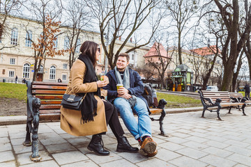 Obraz premium young adult couple eating fast food on bench of city park