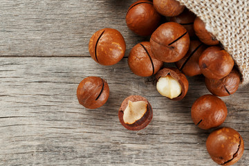 Macadamia nut on a wooden table in a bag, closeup, top view