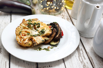 Baked cauliflower with mushrooms served with herbs.