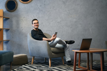 Young man working with phone and computer, receiving phone call, talking with partners 