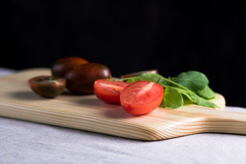 fresh ripe tomatoes on a cutting board with greenery in the background 