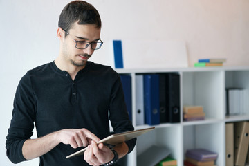 Young man working with tablet, receiving video call, talking with partners 