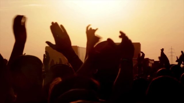 Unrecognizable people holding hands up during concert