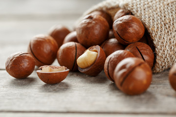Macadamia nut on a wooden table in a bag, closeup, top view