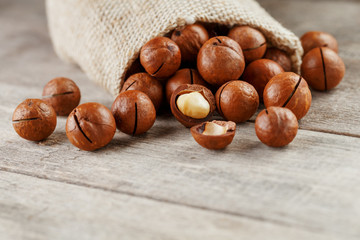 Macadamia nut on a wooden table in a bag, closeup, top view