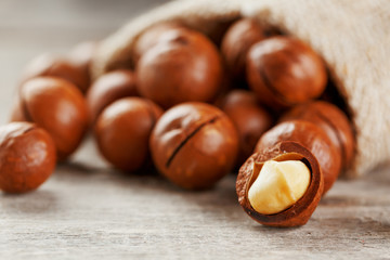 Macadamia nut on a wooden table in a bag, closeup, top view