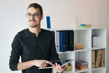 Young man working with tablet, receiving video call, talking with partners 