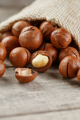 Macadamia nut on a wooden table in a bag, closeup, top view