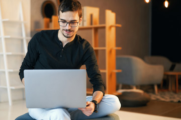 Young man sitting with computer. Freelancer in glasses working with laptop, project manager.