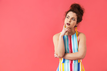 Pensive pretty redhead woman in dress holding her chin