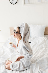 Obraz na płótnie Canvas happy stylish woman in bathrobe and sunglasses, towel and jewelry drinking coffee in bed