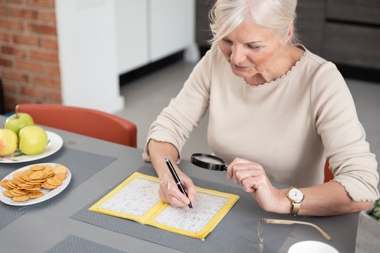 Senior Woman Enjoys Solving A Crossword Puzzle