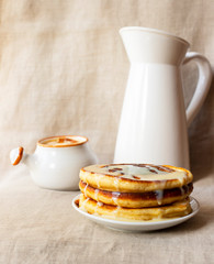 Delicious homemade pancakes with caramel sauce and milk. Close-up. Light background