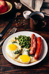 Breakfast with fried eggs, sausages and green peas