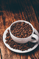 White cup full of roasted coffee beans