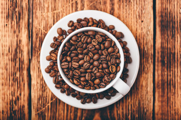 White cup full of roasted coffee beans