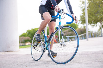 Fototapeta na wymiar Unrecognizable young male cyclist in sportswear cycling bike on road in park