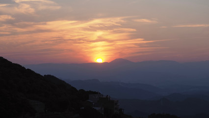Beautiful scenery of mountain range orange sunset with layers of mountain in far away distance.