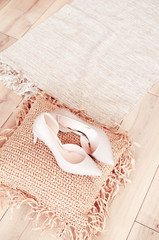 beige high-heeled shoes elegant leather women's shoes on a wooden background light glossy heel shoes on a pillow of straw.