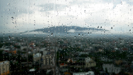 Raindrops on the window and the mountain with the city in blur background.