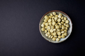 Bio Green BARLEY GRASS tablets. Concept for a healthy dietary supplementation. Black background. Top view. Copy space. 