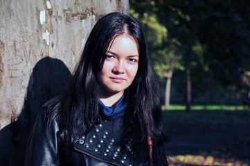 Model posing in a leather jacket in the park on a bright autumn day