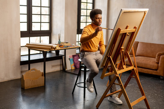 Pleasant creative man holding a brush in his hands