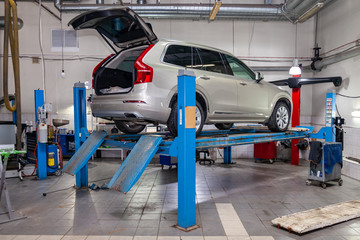 Beige used car stands on the stand wheel alignment convergence of the car in the workshop for...