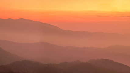 Fototapeta na wymiar Mountain view evening of Top hill around with soft fog with yellow and red sun light in the sky background, sunset at Huai Nam Dang National Park, Chiang Mai, Thailand.