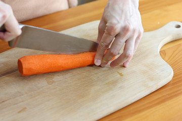 woman cutting carrot on wooden board