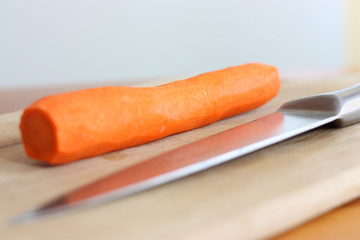 fresh carrots and knife on cutting board
