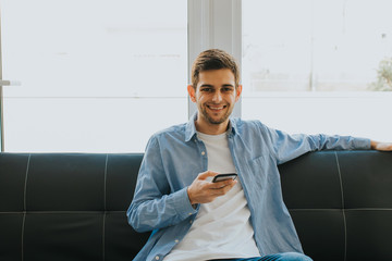 young man or teenager with mobile phone indoors