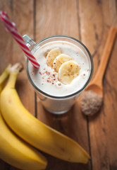 Close-up of banana and flax seeds smoothie in a glass on wooden background