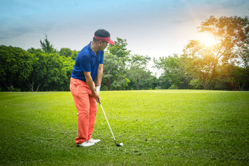 Golfer playing golf on the sand in the evening golf course, on sun set evening time.