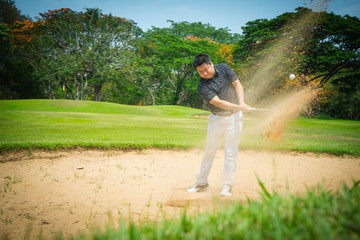 Blurred golfer playing golf on the sand in the evening golf course, on sun set evening time.